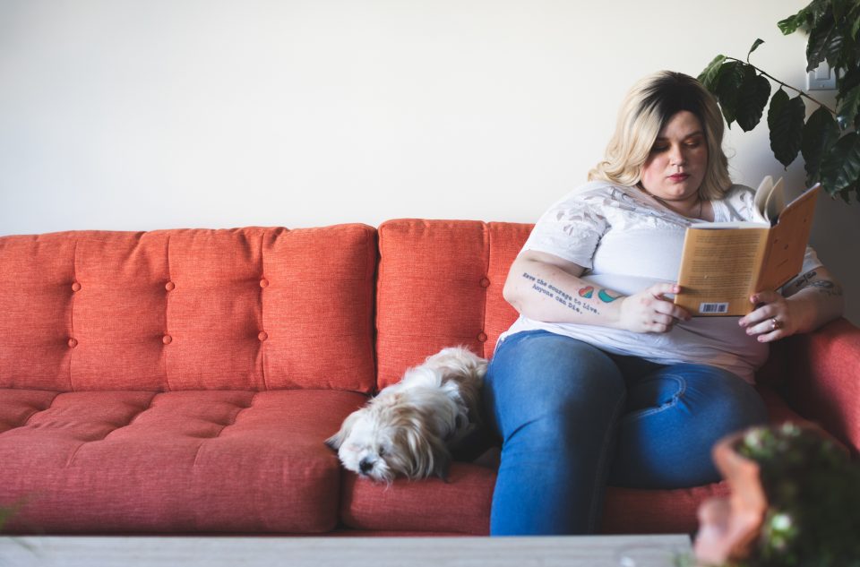 ragazza sovrappeso seduta col cane legge un libro