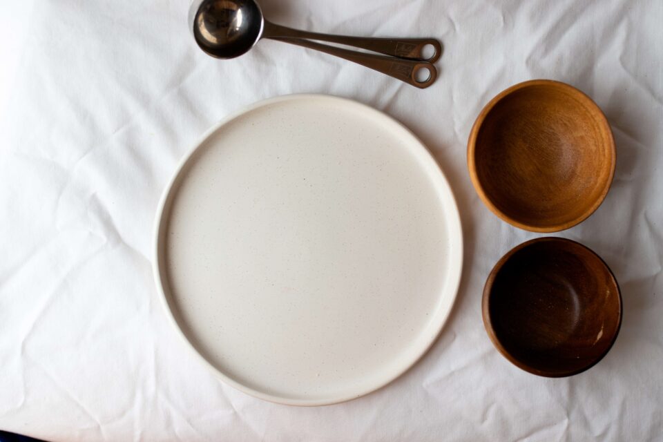Un piatto e due ciotole vuote sullo sfondo di una tovaglia stropicciata bianca a rappresentare i DCA